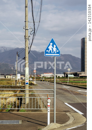 山を背景に立つ子供の横断を知らせる道路標識 142310384