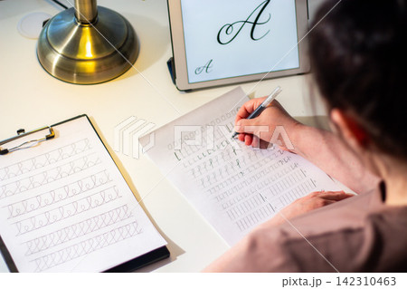 Woman sitting at desk and writing with pen. Handwriting boosts memory retention concept. Close up of pen on paper, deep concentration, analog study habits for better learning 142310463