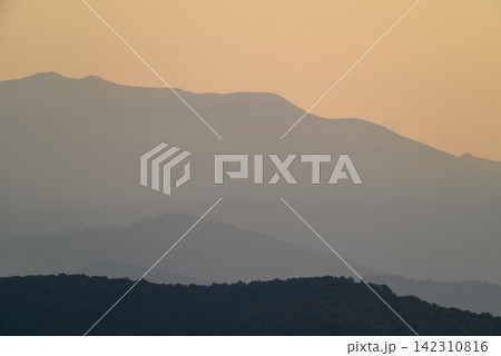 A serene landscape dominated by layered mountain ranges receding into the distance A serene landscape dominated by layered mountain ranges receding into the distance 142310816