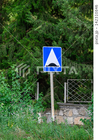 A detailed road sign in a rustic outdoor setting against lush green grass and dense coniferous trees A detailed road sign in a rustic outdoor setting against lush green grass and dense coniferous trees 142310846