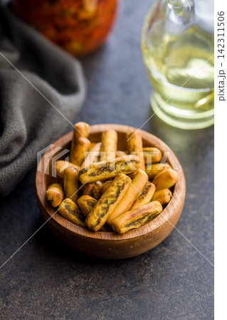 Savory Breadstick Snack Sticks in Wooden Bowl with Olive Oil on Rustic Table Savory Breadstick Snack Sticks in Wooden Bowl with Olive Oil on Rustic Table 142311506