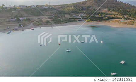 Aerial high angle view of Tbilisi Reservoir coastline with small boats anchored on calm green water near sandy beach during sunset horizontal stock photo Aerial high angle view of Tbilisi Reservoir coastline with small boats anchored on calm green water near sandy beach during sunset horizontal stock photo 142311553