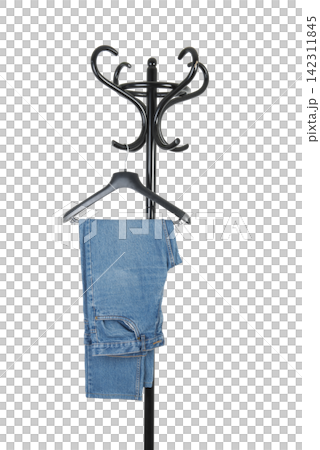 A pair of blue jeans hangs from a black hanger on a black coat rack A pair of blue jeans hangs from a black hanger on a black coat rack 142311845