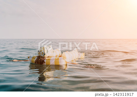 Person Floating Ocean Gifts: A person swims in the ocean with several wrapped gifts as a makeshift flotation device. Person Floating Ocean Gifts: A person swims in the ocean with several wrapped gifts as a makeshift flotation device. 142311917