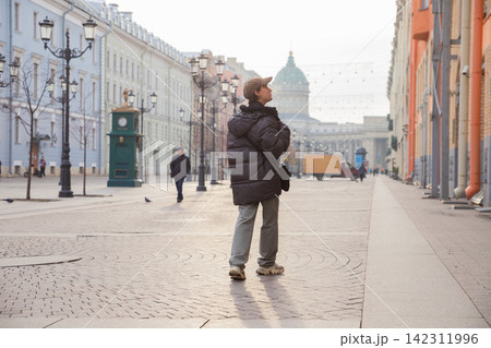 Young man student sightseeing on pedestrian street in central Saint Petersburg with Kazan cathedral in background. Urban tourism and travel exploration concept. Historic architecture 142311996