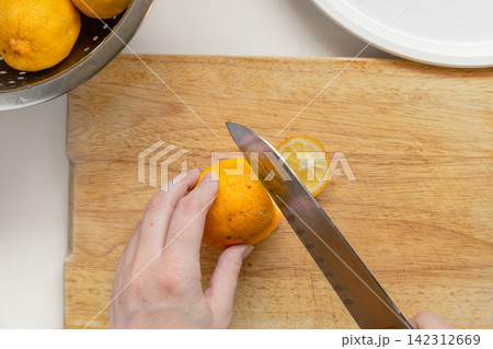 Hand Cutting a Fresh Garden Lemon on a Wooden Cutting Board Hand Cutting a Fresh Garden Lemon on a Wooden Cutting Board 142312669