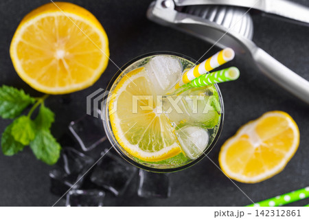 Refreshing homemade lemonade with lemon slices, fresh mint, ice and citrus juicer, cold beverage 142312861