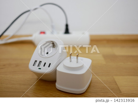 Universal travel adapter close up against the backdrop of a socket. Electric plug adapter, international plug socket gadget for travel. 142313916