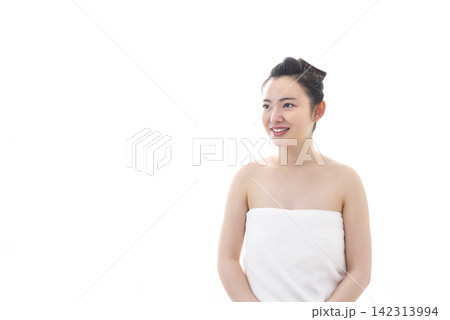 白バックでバスタオルを巻いて微笑む若い女性 白バックでバスタオルを巻いて微笑む若い女性 142313994