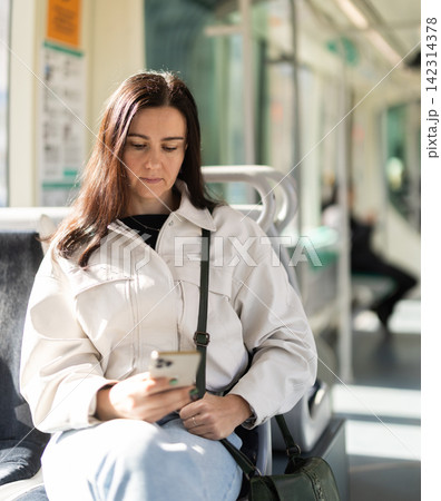 Girl sitting in modern tramway car, scrolls through social media feed Girl sitting in modern tramway car, scrolls through social media feed 142314378