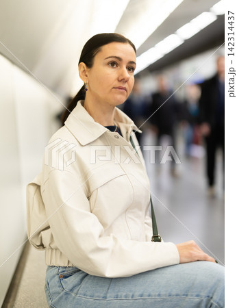 Girl is sitting on metro platform station, waiting for transport to arrive 142314437