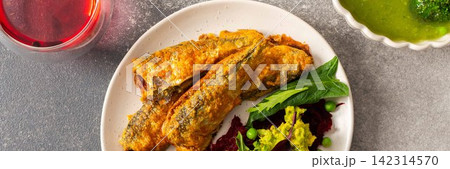 Baked small sea fish is served alongside boiled beets, hummus, green peas, and herbs. This dish is suitable for breakfast and offers a healthy option, banner 142314570