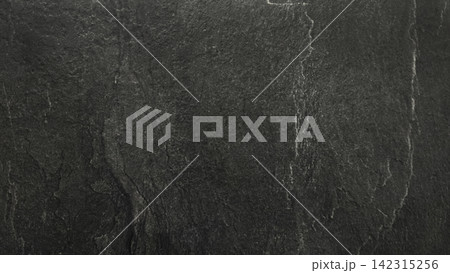 Dark black natural stone surface with subtle cracks, rough texture and weathered details. Abstract slate background with a dramatic charcoal gray pattern. Dark black natural stone surface with subtle cracks, rough texture and weathered details. Abstract slate background with a dramatic charcoal gray pattern. 142315256