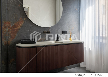 Floating bathroom vanity with a large round mirror showing clear geometry Floating bathroom vanity with a large round mirror showing clear geometry 142315660