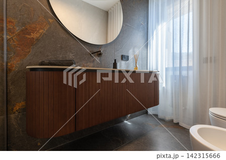 Bathroom vanity shown with freestanding bathtub against charcoal panels and warm wood Bathroom vanity shown with freestanding bathtub against charcoal panels and warm wood 142315666