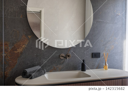 Bathroom vanity styled with rolled towels and reed diffuser in a controlled earthy palette Bathroom vanity styled with rolled towels and reed diffuser in a controlled earthy palette 142315682