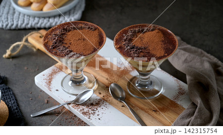 Two glasses of classic Italian tiramisu topped with cocoa powder and dark chocolate shavings Two glasses of classic Italian tiramisu topped with cocoa powder and dark chocolate shavings 142315754