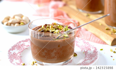 A glass of chocolate mousse topped with pistachios A glass of chocolate mousse topped with pistachios 142315898