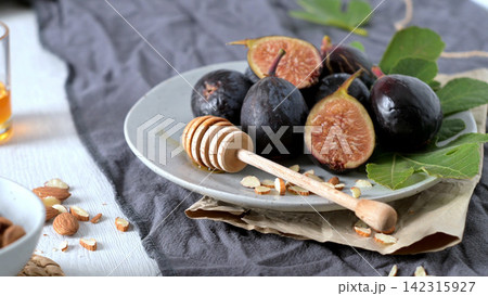 Fresh Figs on a Plate with Honey Dipper and Almonds Fresh Figs on a Plate with Honey Dipper and Almonds 142315927