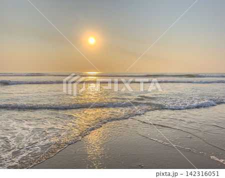 Golden sunset reflecting on ocean waves and wet sand at the beach Golden sunset reflecting on ocean waves and wet sand at the beach 142316051