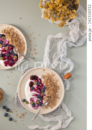Top Down Flat Lay of Yogurt Bowls with Blueberry Swirl and Whole Grain Flakes Top Down Flat Lay of Yogurt Bowls with Blueberry Swirl and Whole Grain Flakes 142316552