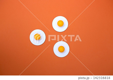 Three yellow balls on white circles on an orange background 142316818