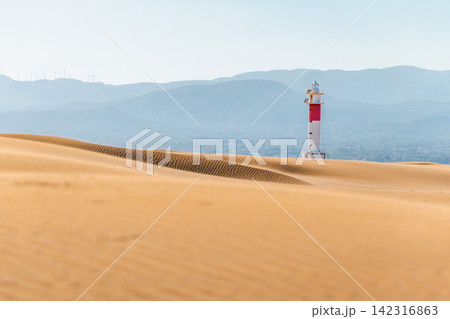 Ebro Delta lighthouse beyond coastal sand dunes in Deltebre, Catalonia, Spain Ebro Delta lighthouse beyond coastal sand dunes in Deltebre, Catalonia, Spain 142316863