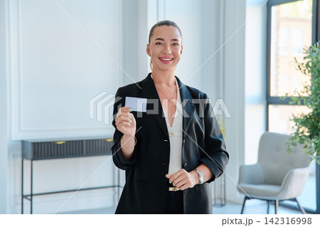 Smiling businesswoman showing blank white plastic credit card in office Smiling businesswoman showing blank white plastic credit card in office 142316998