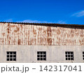 Rusted corrugated metal facade and windows under blue sky 142317041