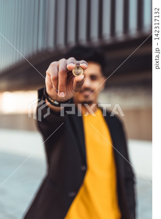 Moroccan man showing euro coin outdoors, finance concept Moroccan man showing euro coin outdoors, finance concept 142317132