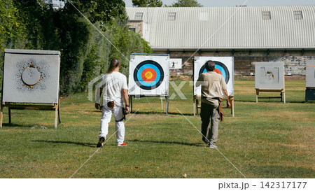 Archers walking towards targets after shooting arrows Archers walking towards targets after shooting arrows 142317177