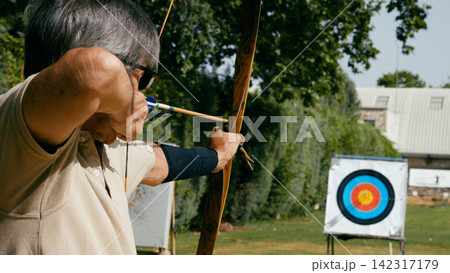 Senior man aiming bow at archery target Senior man aiming bow at archery target 142317179