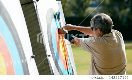 Older man hitting target while practicing archery Older man hitting target while practicing archery 142317195