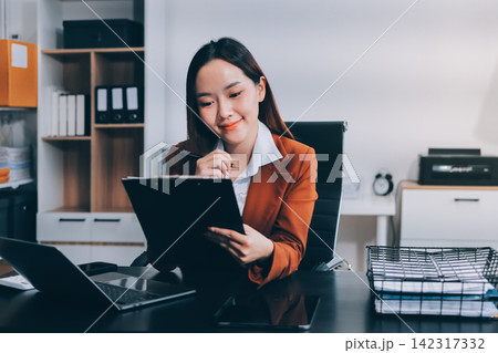 Asian businesswoman using calculator and working on laptop at modern office Asian businesswoman using calculator and working on laptop at modern office 142317332