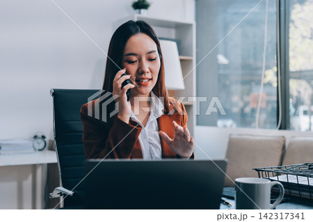 Female secretary who works in the office is talking on the phone with someone. Female secretary who works in the office is talking on the phone with someone. 142317341