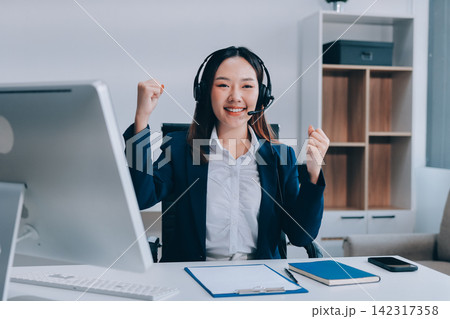 Smiling Asian Woman Telemarketing Agent with Headset Working at Smiling Asian Woman Telemarketing Agent with Headset Working at 142317358