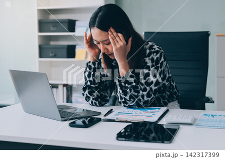 Tried young Asian office employee feeling sick and have a headache from a long working day at office Tried young Asian office employee feeling sick and have a headache from a long working day at office 142317399