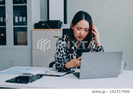 Tried young Asian office employee feeling sick and have a headache from a long working day at office Tried young Asian office employee feeling sick and have a headache from a long working day at office 142317400