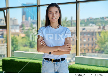 Young woman standing with arms crossed in front of panoramic window portrait 142317829