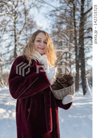 Woman collecting pine cones in snowy winter forest Woman collecting pine cones in snowy winter forest 142318328
