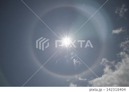 太陽の周りに広がる神秘的なハロー現象、青空に浮かぶ白い光の輪 142318404