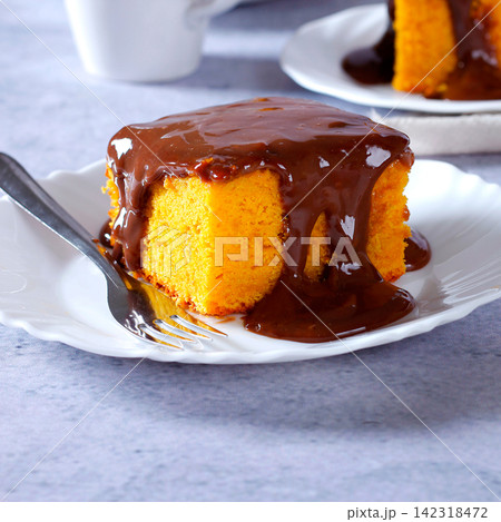 Brazilian carrot cake with a soft crumb, topped with creamy chocolate, on a white plate Brazilian carrot cake with a soft crumb, topped with creamy chocolate, on a white plate 142318472
