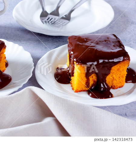 Brazilian carrot cake with a soft crumb and creamy chocolate frosting on a white plate. 142318473