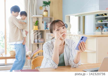 育児しながらスマホを見る母親 育児しながらスマホを見る母親 142320736