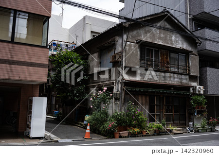多くの植木鉢と木製の引き戸が温かみを感じさせる、モルタル壁のレトロな古い家屋 多くの植木鉢と木製の引き戸が温かみを感じさせる、モルタル壁のレトロな古い家屋 142320960