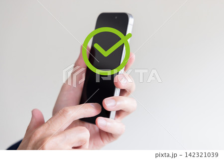スマートフォンを操作してチェックマークで完了・承認を確認するビジネスイメージ 142321039