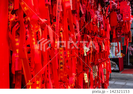 red wishing ribbons tied on tree branches near stone guardian lion for good luck red wishing ribbons tied on tree branches near stone guardian lion for good luck 142321153