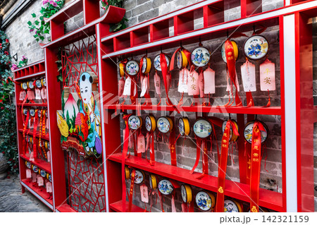 folk wishing wall decorated with red ribbons and traditional Chinese paper crafts for blessings 142321159