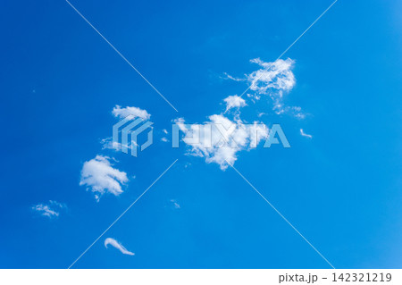 low angle view of clear blue sky with soft white clouds on a sunny day 142321219