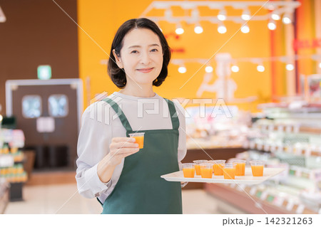 スーパーマーケットで試飲用ドリンクを提供する女性スタッフ 142321263